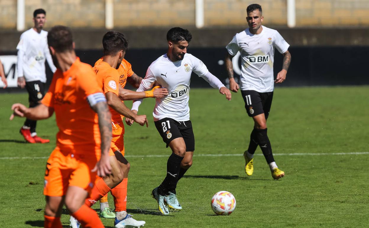 Chema Núñez conduce el balón ante la vigilancia de dos jugadores del Alcoyano. 