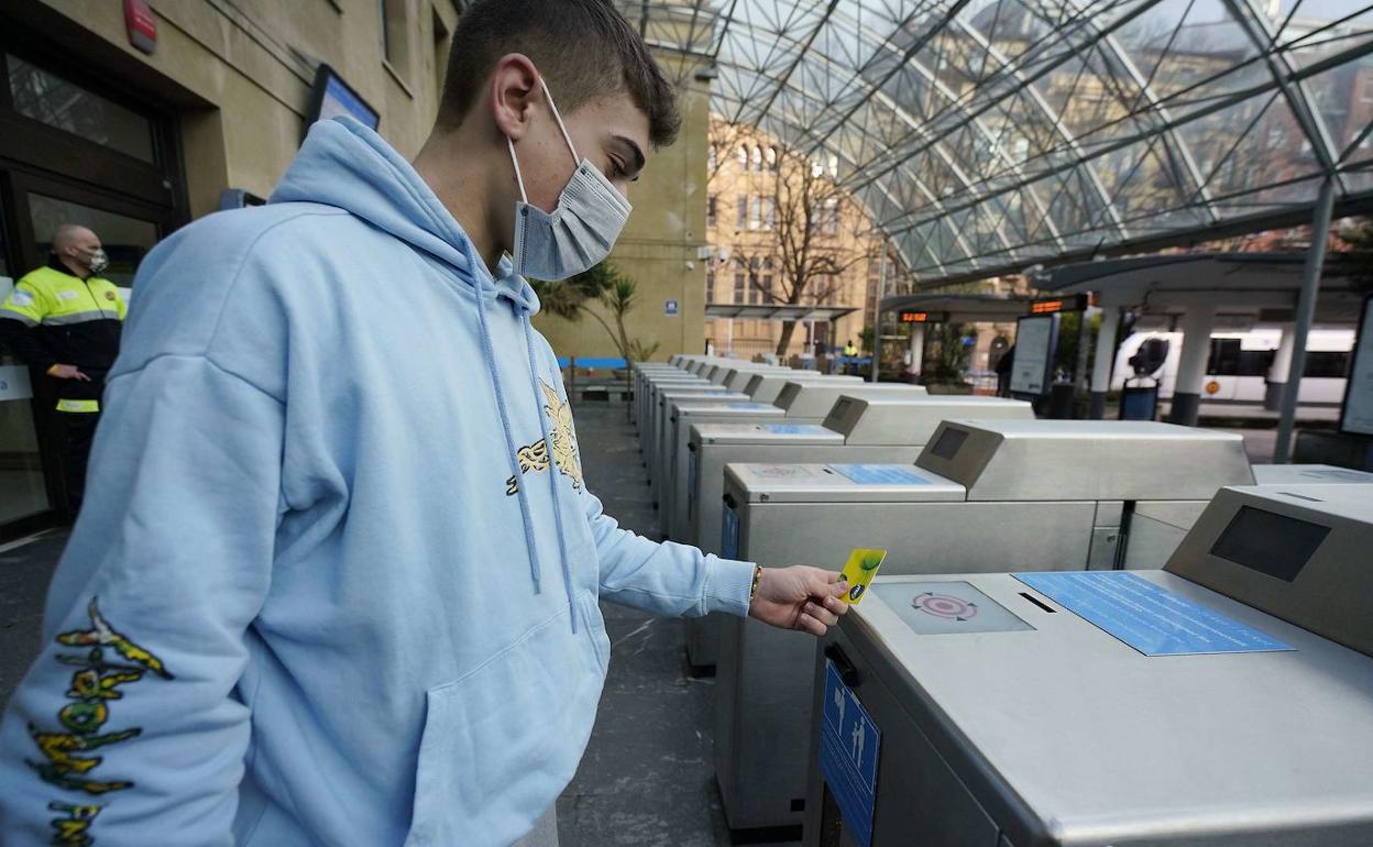 Un joven se dispone a pasar su tarjeta Mugi por el torno de entrada a la estación del Topo de Easo.