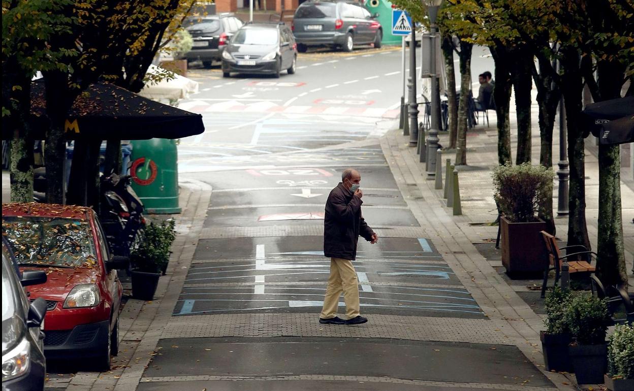 Un hombre cruza una calle de Astigarraga con mascarilla. 