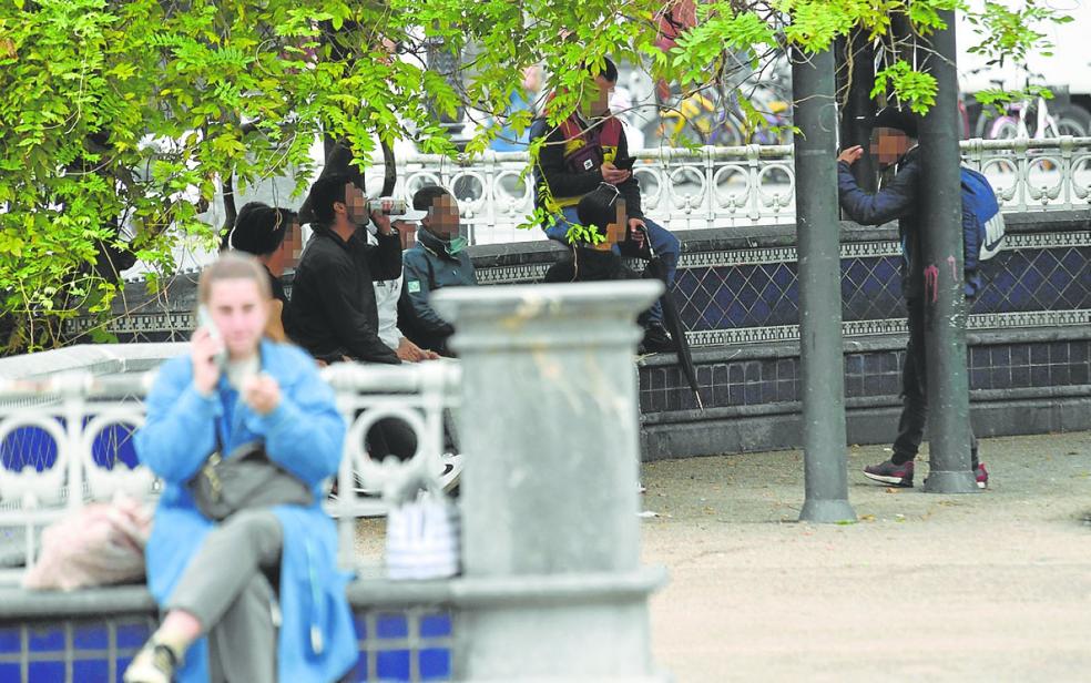 Varios hombres jóvenes beben latas de cerveza en la plaza Easo. 