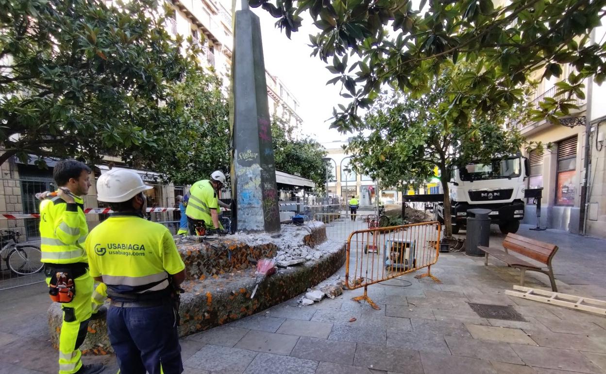 Varios obreros participan en la demolición del banco corrido central de la plaza Sarriegi. 