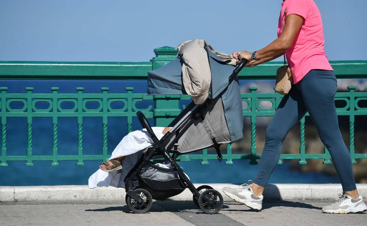 Una mujer pasea a un recién nacido por Donostia. 