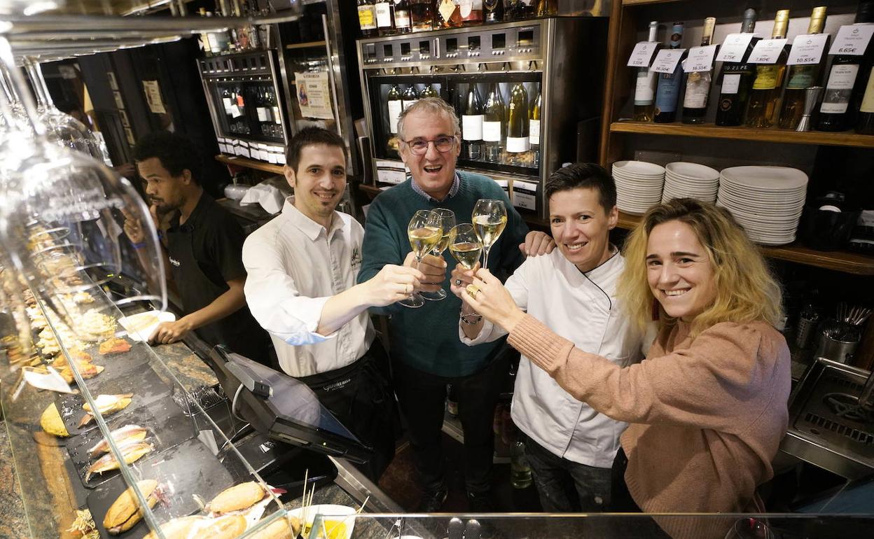Los responsables del reconocido Gandarias brindan ante la barra del restaurante, poblada, de pinchos.