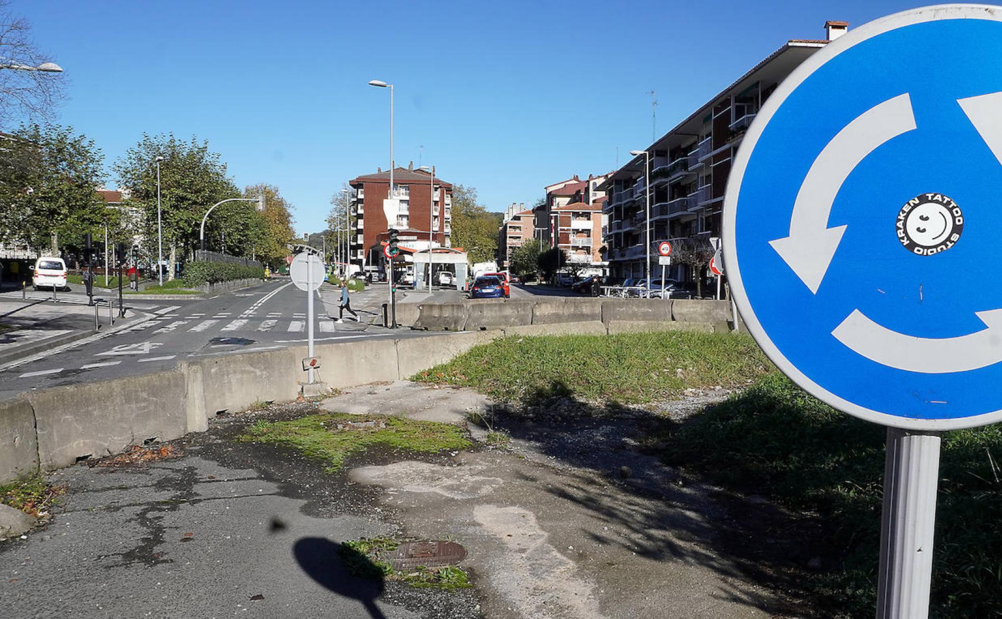 La rotonda del barrio, con vallas de obra, suciedad, hierbajos y cemento. 