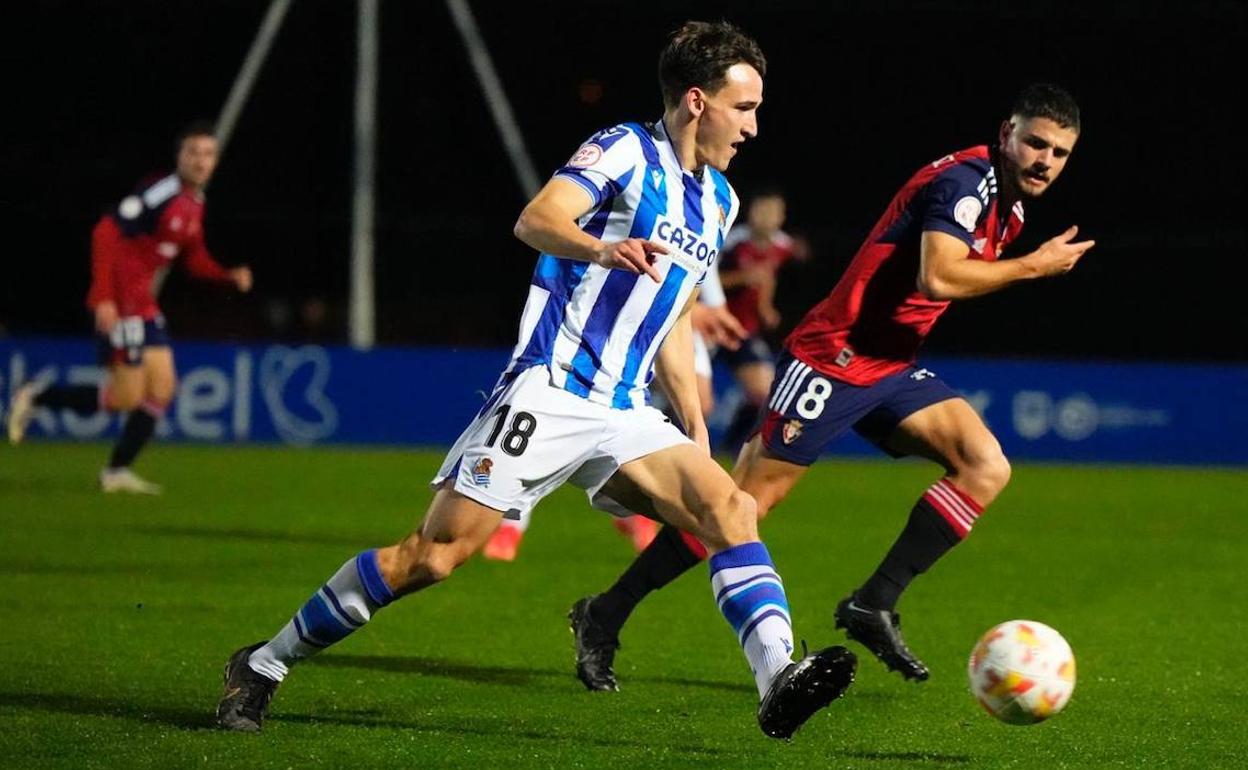 Kortajarena conduce el balón seguido de cerca por un jugador osasunista. 