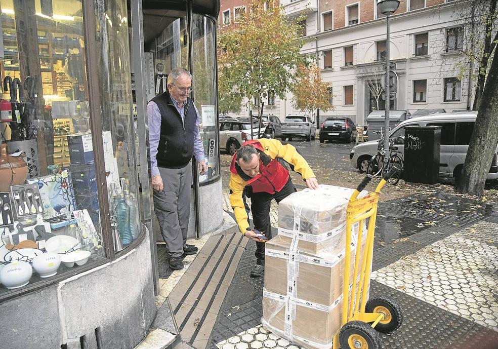 Ioritz Rojo desembala, ante la entrada de una ferretería, varios paquetes envueltos en plástico para protegerlos de la lluvia. El profesional debe velar por que losbultos lleguen en buen estado. 