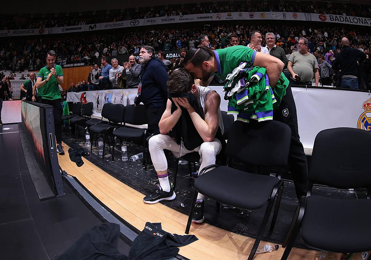 Brizuela, emocionado en su banquillo tras la victoria, es consolado por uno de los compañeros del Unicaja de Málaga.