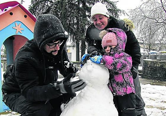 La pequeña Nora, de 4 años, haciendo un muñeco de nieve en Arrasate con ayuda de sus padres.