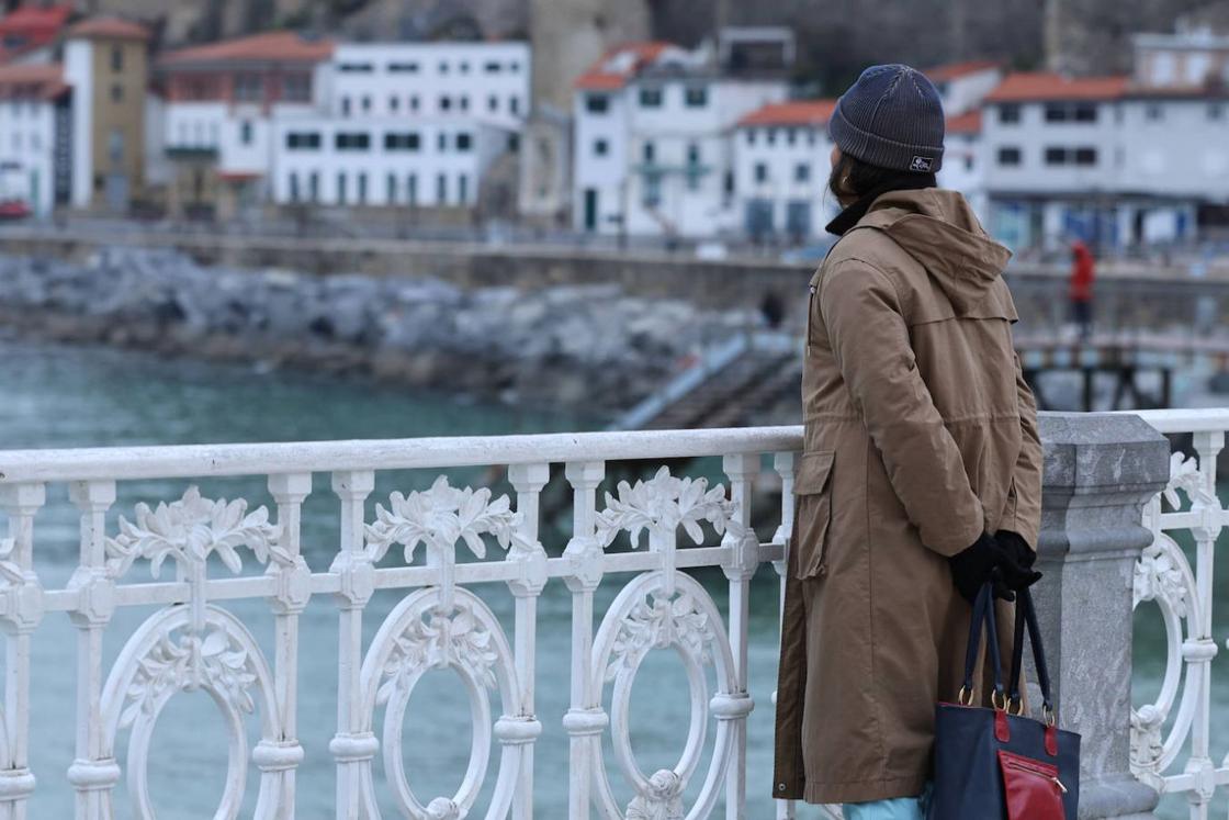 Una mujer observa la bahía de La Concha con el kit completo de guantes, gorro y abrigo.