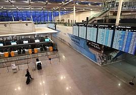 Un pasajero camina por la terminal desierta del aeropuerto de Munich y observa los paneles con todas las cancelaciones.