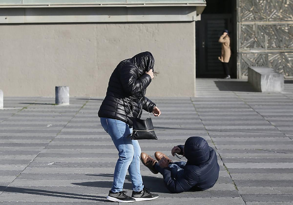 Un hombre cae al suelo en el Kursaal por una fuerte racha de viento este domingo por la tarde.