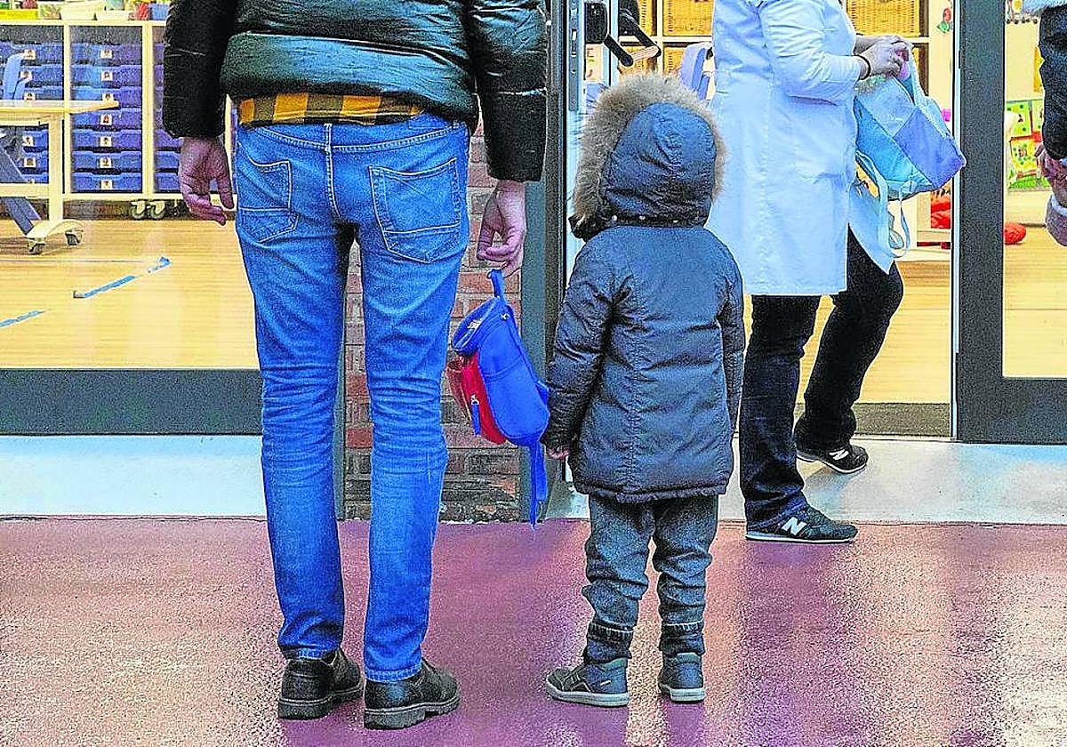 Escolares de infantil, acompañados de sus padres, en la entrada de un colegio.