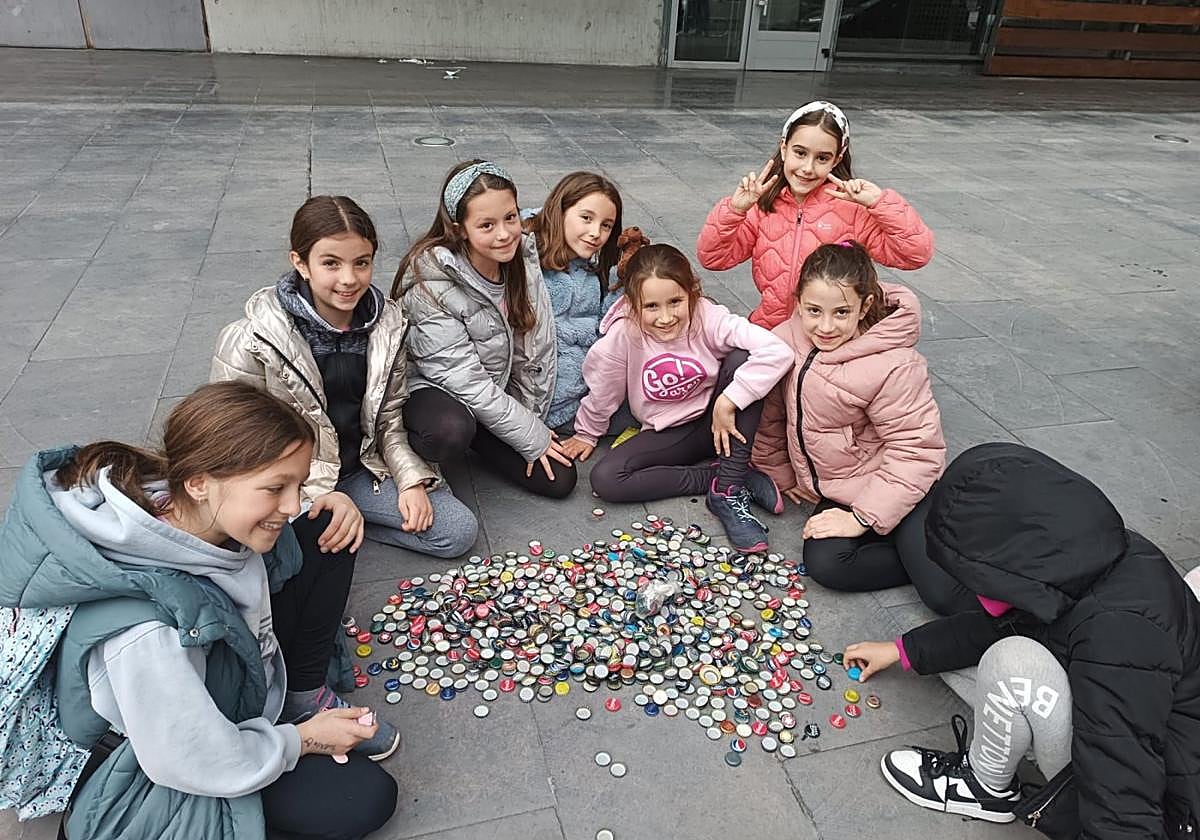 Varios niños muestran su colección de chapas tras una tarde buscándolas por los bares.