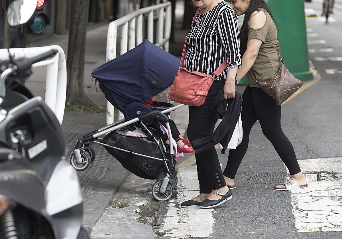 Una usuaria trata de subir el carro de su bebé en un paso de cebra de la calle Etxaide de Donostia