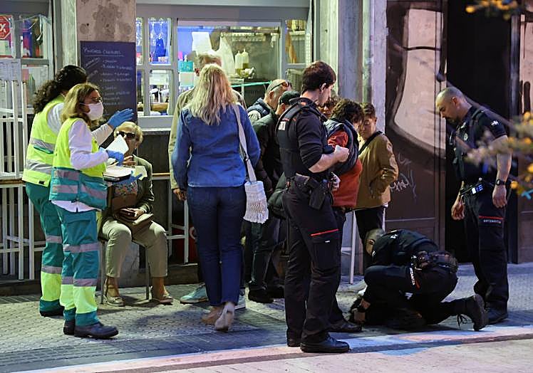 Imagen principal - Sanitarios y ertzainas atienden a varias personas de la terraza y a un perro, abajo a la derecha. Ertzaintza y Guardia Municipal en la calle Carquizano de San Sebastián.