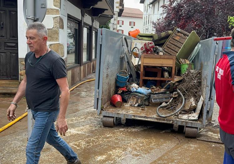 Imagen principal - Los vecinos limpian las calle de Bera tras la lluvia torrencial que ha caído esta madrugada. 