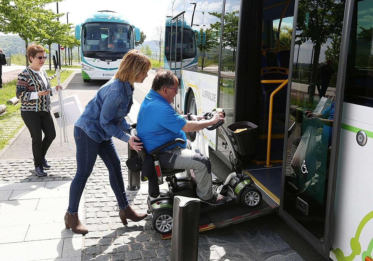 Un hombre en silla de ruedas accede a un autobús con ayuda de una acompañante.