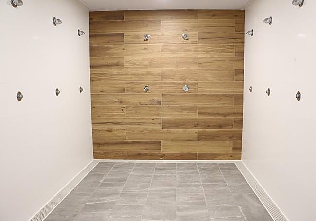Las nuevas duchas con revestimiento de madera en la pared.