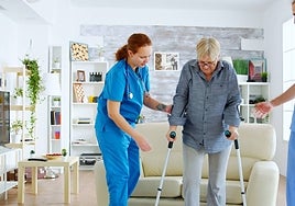 Dos enfermeros ayudan a una mujer usuaria de una residencia.