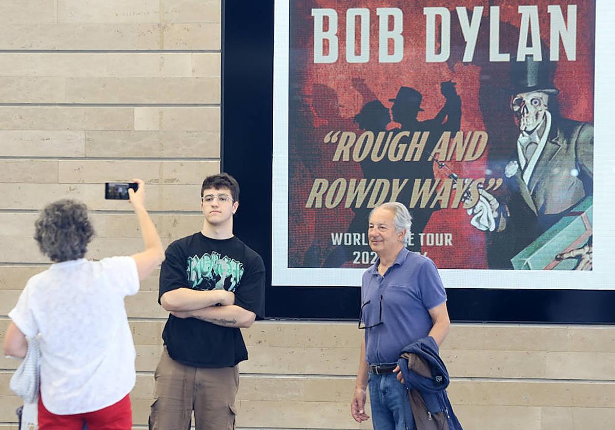 Unos fans de Dylan se fotografían con el cartel del concierto detrás.