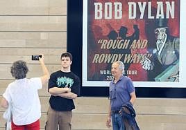 Unos fans de Dylan se fotografían con el cartel del concierto detrás.