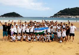 Jugadores y miembros del staff técnico del Metallurg de Uzbekistán posan en la playa de la Concha junto con la bandera de su país.