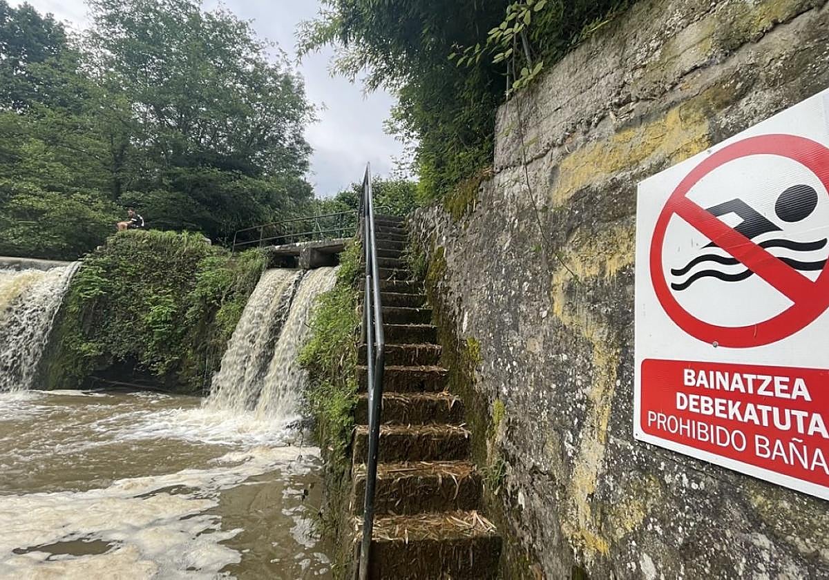 Cartel que advierte de la prohibición de baño en la poza, que ayer estaba muy turbia por las tormentas.