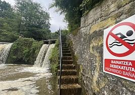 Cartel que advierte de la prohibición de baño en la poza, que ayer estaba muy turbia por las tormentas.