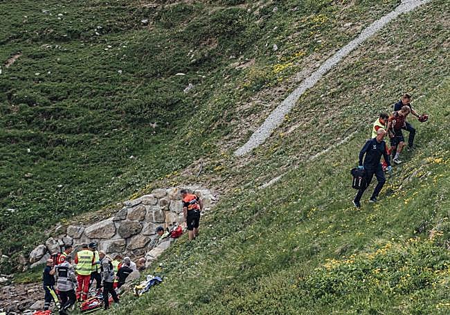 Magnus Sheffield es acompañado barranco arriba por dos sanitarios mientras el resto atiende al fallecido Gino Mäder.