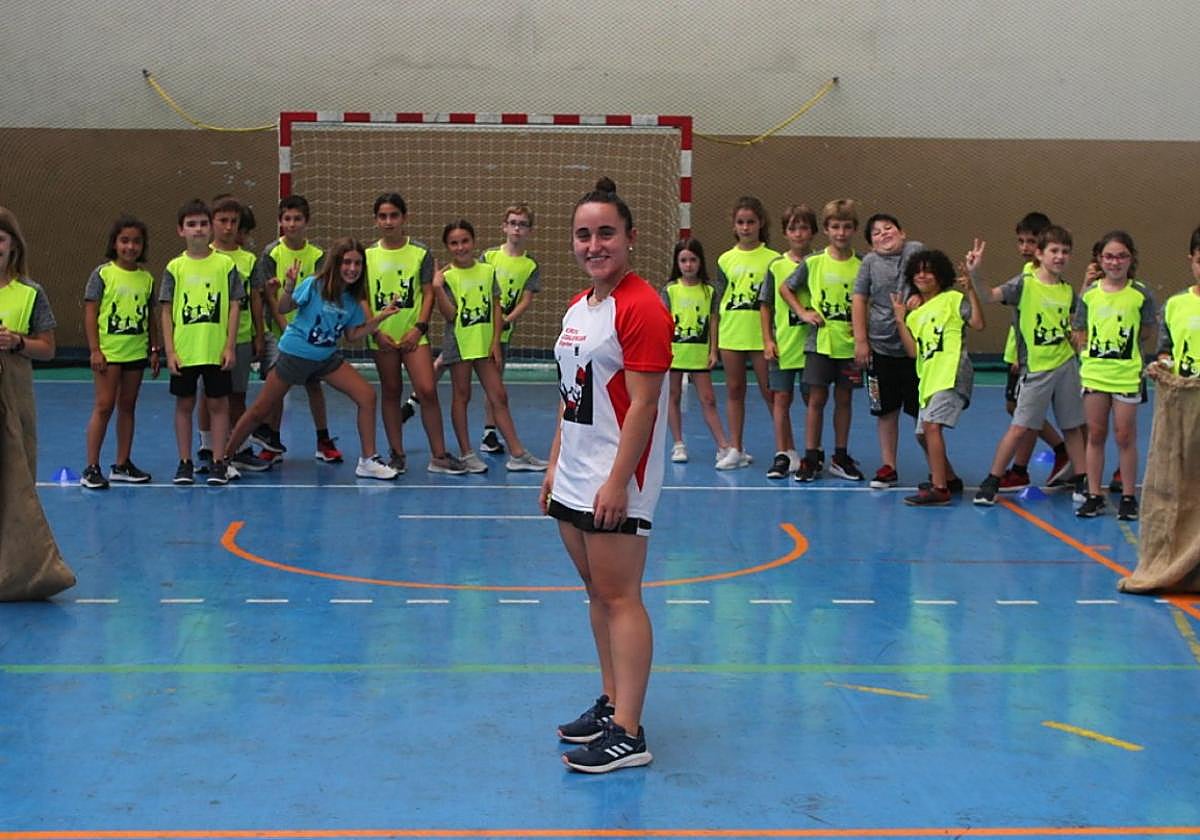 Participantes en el campus deportivo de verano practican carreras de sacos en la cancha del polideportivo.