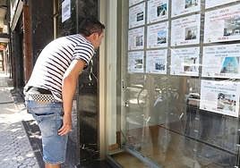 Un joven consulta el escaparate de una inmobiliaria.