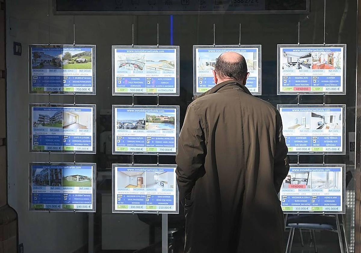 Un hombre mira el escaparate de una agencia inmobiliaria.