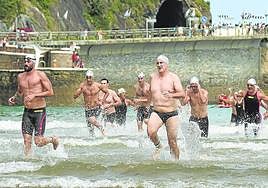 Los participantes abandonan el agua en la playa de Zarautz tras completar la travesía.