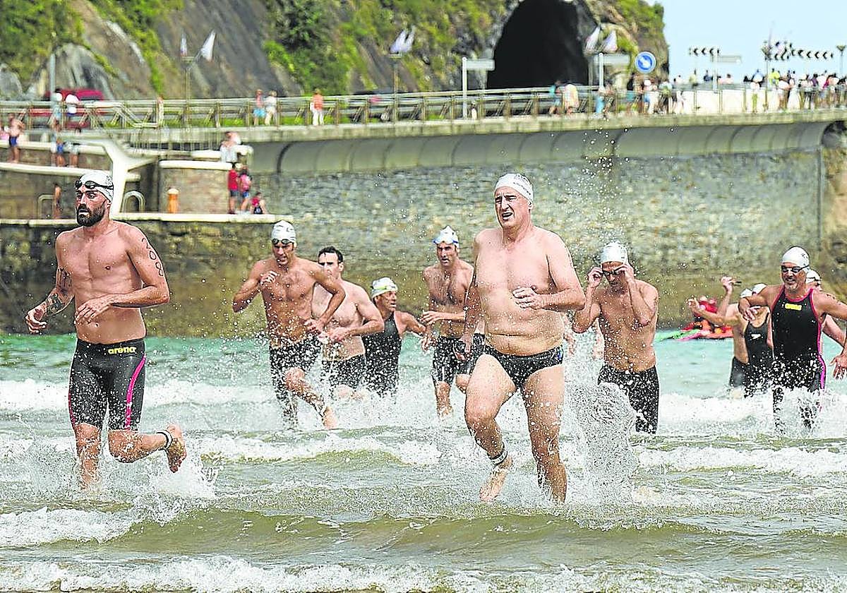 Los participantes abandonan el agua en la playa de Zarautz tras completar la travesía.