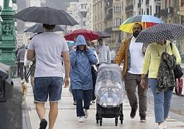 Paseantes se camuflan de la lluvia bajo los paraguas en San Sebastián.