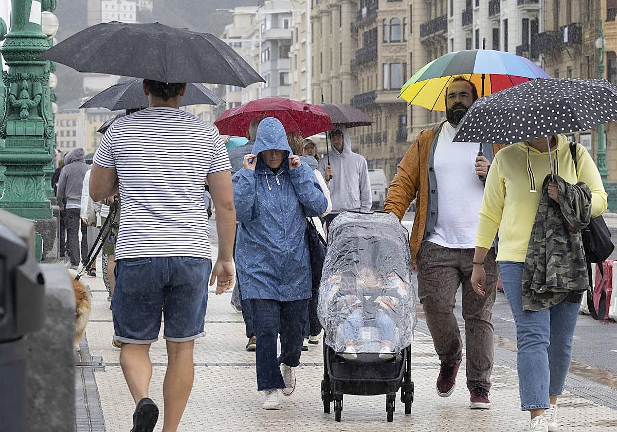 Paseantes se camuflan de la lluvia bajo los paraguas en San Sebastián.