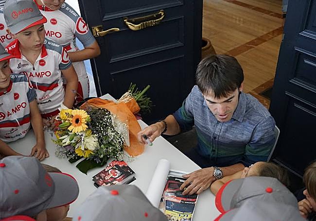 Ion Izagirre firma cartulinas con la foto de su victoria a los jóvenes del club ciclista Ampo.