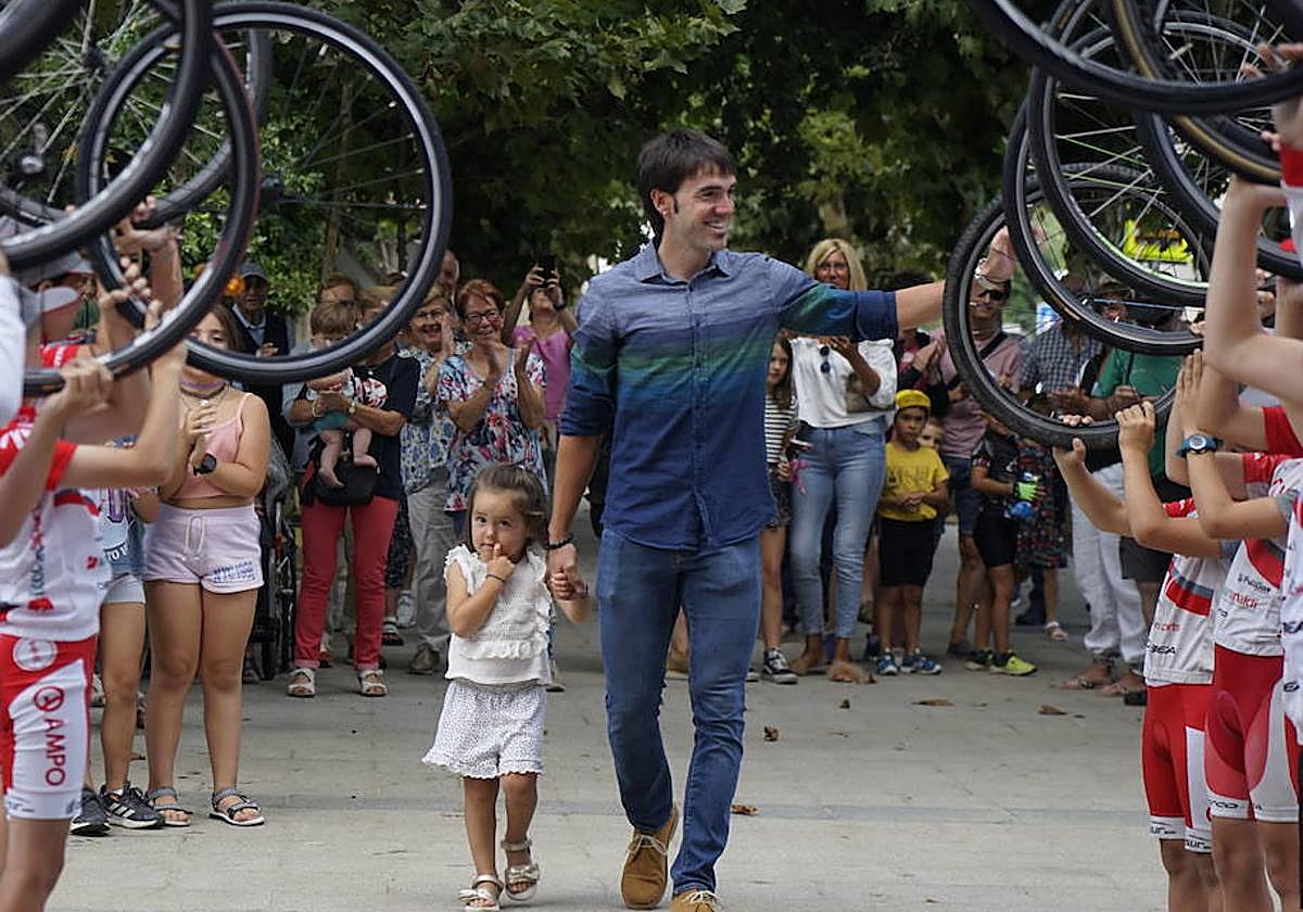 Ion Izagirre camina junto a su hija Iraia, que cumplió tres años el día de su victoria, entre el pasillo que formaron los ciclistas del Ampo en Ormaiztegi.