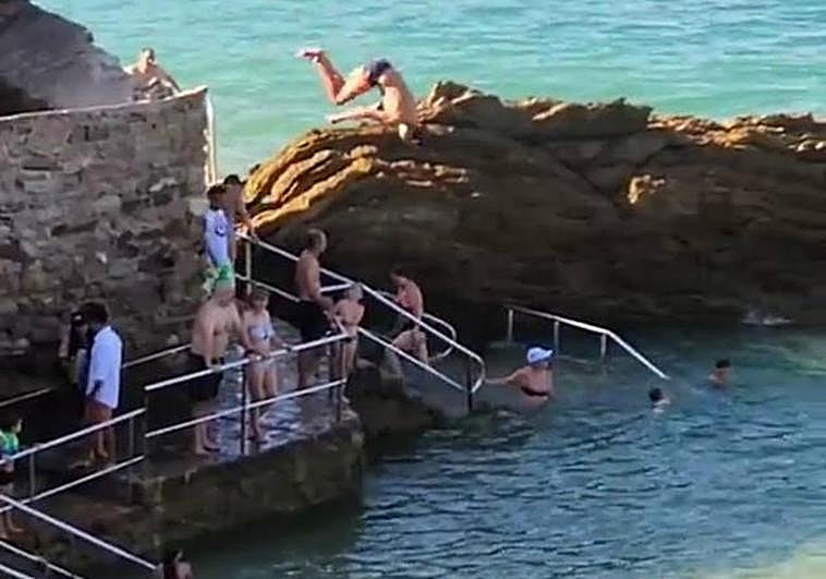 Un joven se tira al agua desde el Pico del Loro de San Sebastián con voltereta incluida.
