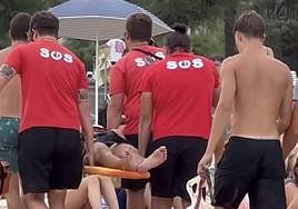 Socorristas de la playa de Ondarreta rescatan este miércoles al joven herido por el impacto con una ola.