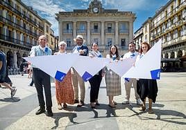 Comerciantes colaboradores en el reparto de pañuelos posan con los diseños de este año en la Plaza de la Constitución.