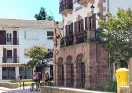 Dos cicloturistas, ante el Ayuntamiento de Doneztebe, con la bandera a medio asta y un crespón negro.