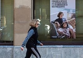 Una mujer pasea por delante de una entidad financiera.