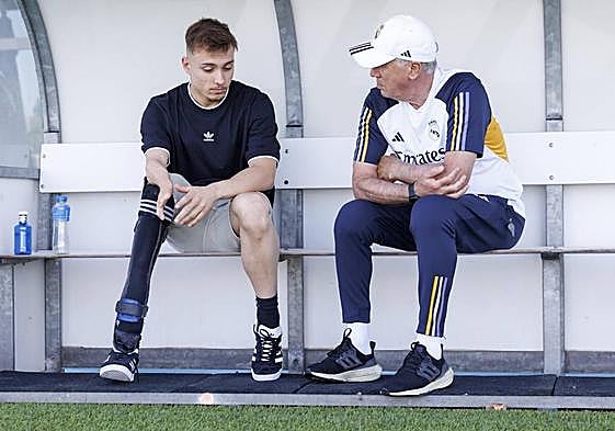 Iñigo Llopis y Carlo Ancelotti conversan en el banquillo del campo de entrenamiento del Real Madrid en Valdebebas.
