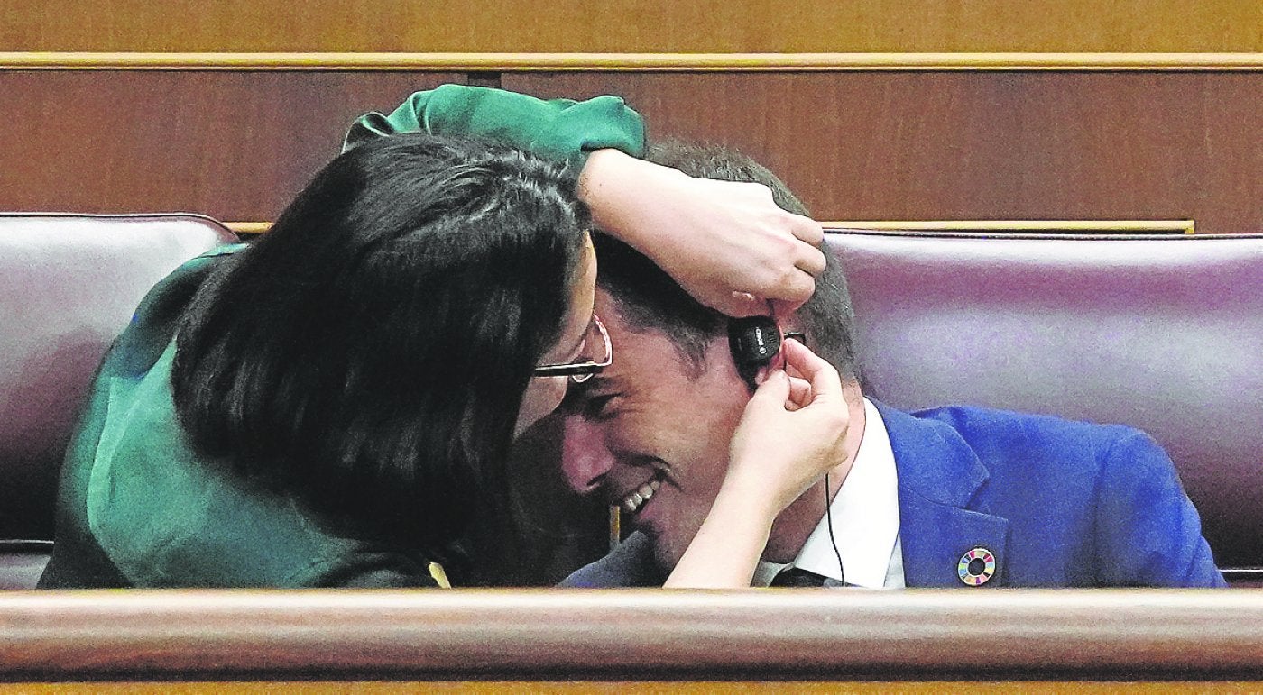 Una diputada ayuda a su compañero a colocarse el auricular.