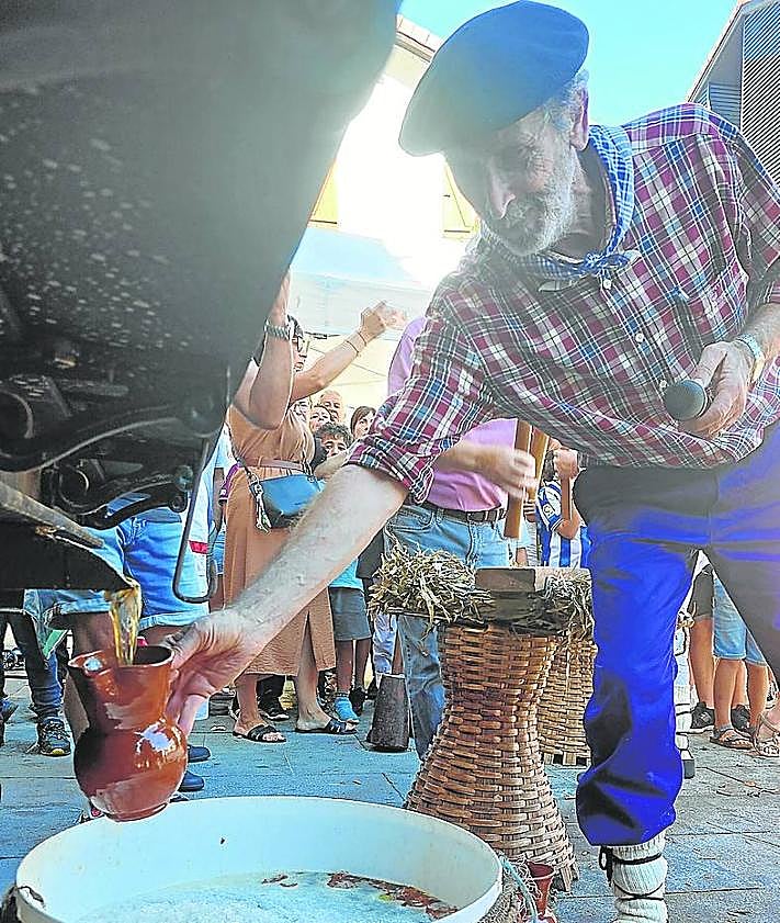 Imagen secundaria 2 - Dantzaris de Astigar bailaron la 'sagar dantza', los niños disfrutaron ayudando a elaborar el dulce clado y los asistentes probando el primer mosto. 