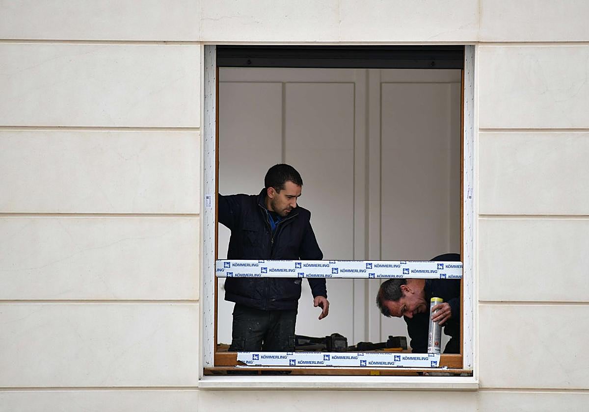 Dos trabajadores realizan trabajos de rehabilitación en una vivienda.