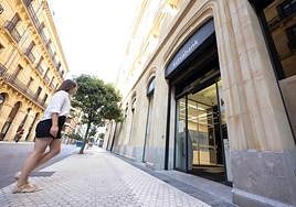 Una mujer se dispone a entrar a una oficina de Kutxabank en el centro de Donostia.