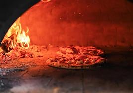 Una pizza en el horno de una pizzería.
