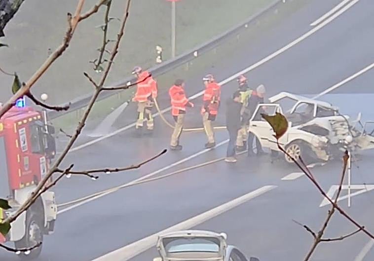 Los bomberos limpian la calzada en la zona en la que se ha producido el accidente.